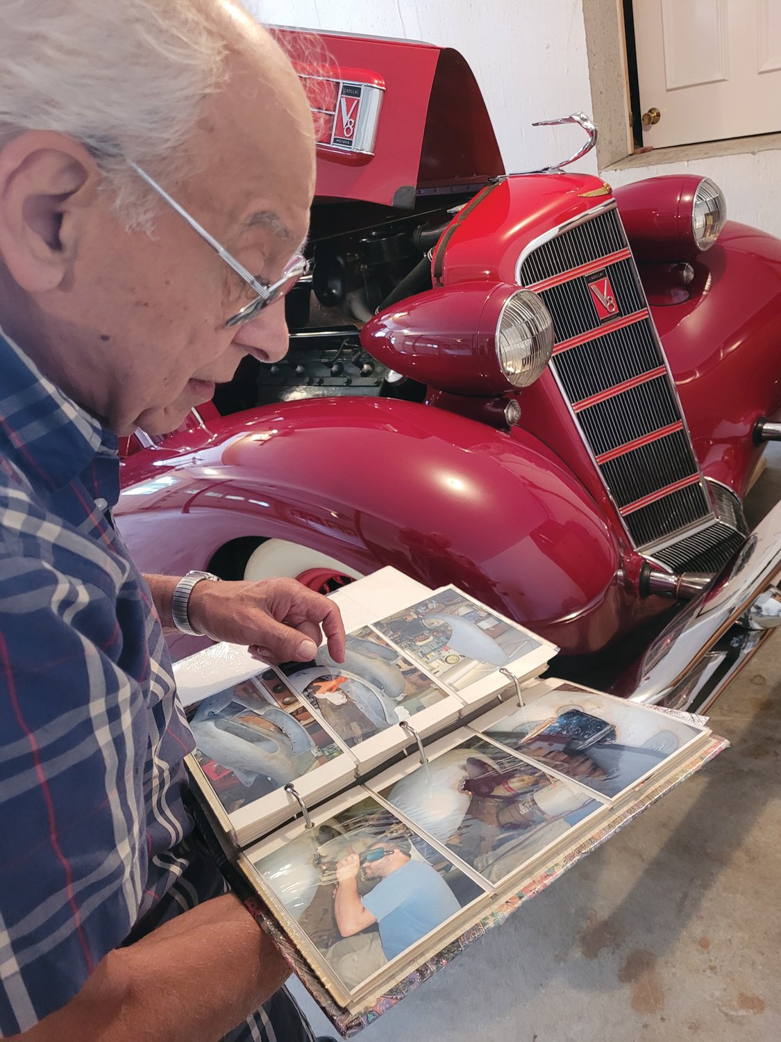 PHOTOGRAPHIC JOURNAL: John Ricci pages through two albums full of snapshots taken during his decades-long restoration.